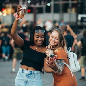 Friends using smartphone and drinking beer on a music festival